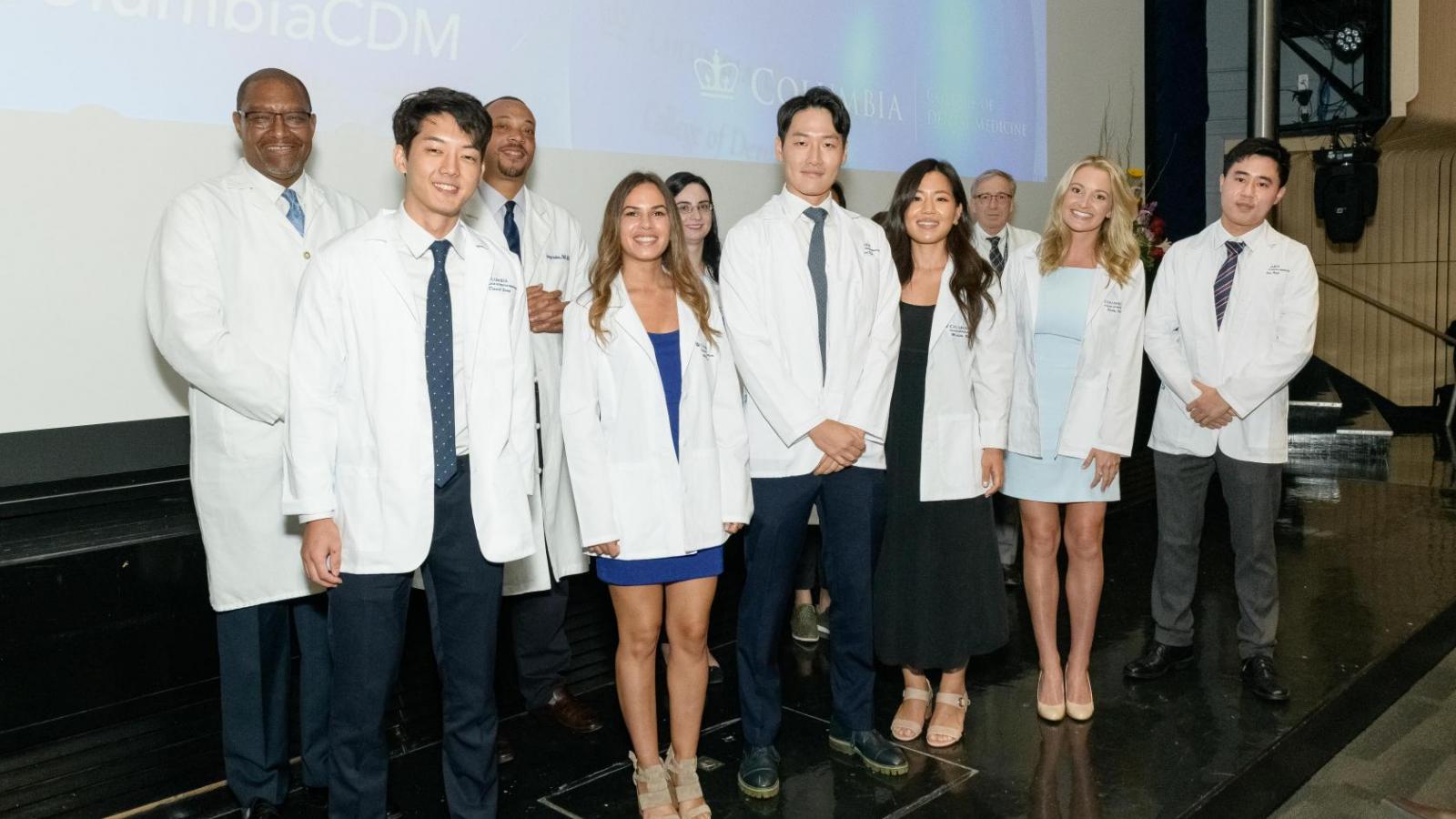 Group of students wearing white coats on stage