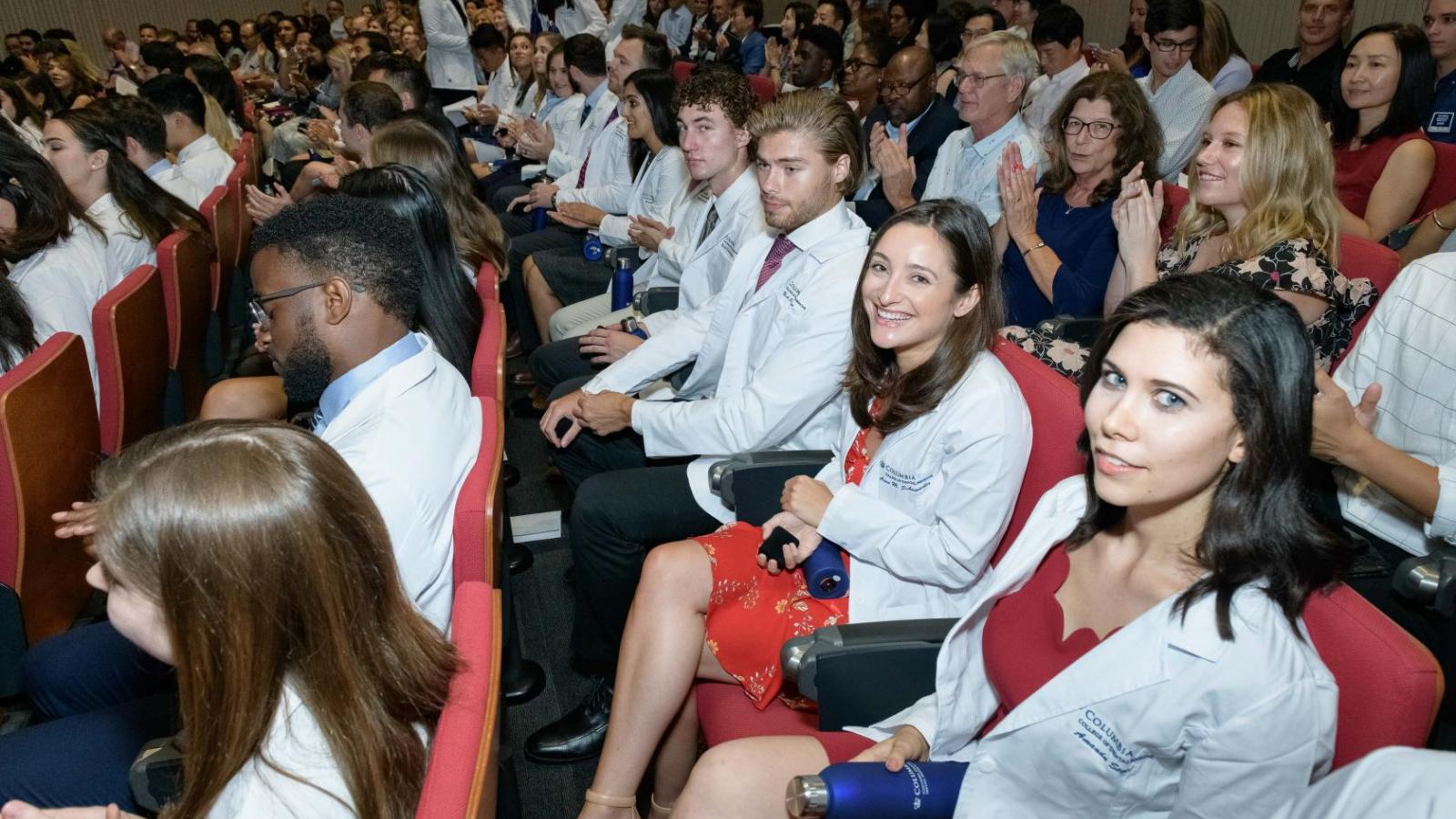 Students seated after receiving their white coats