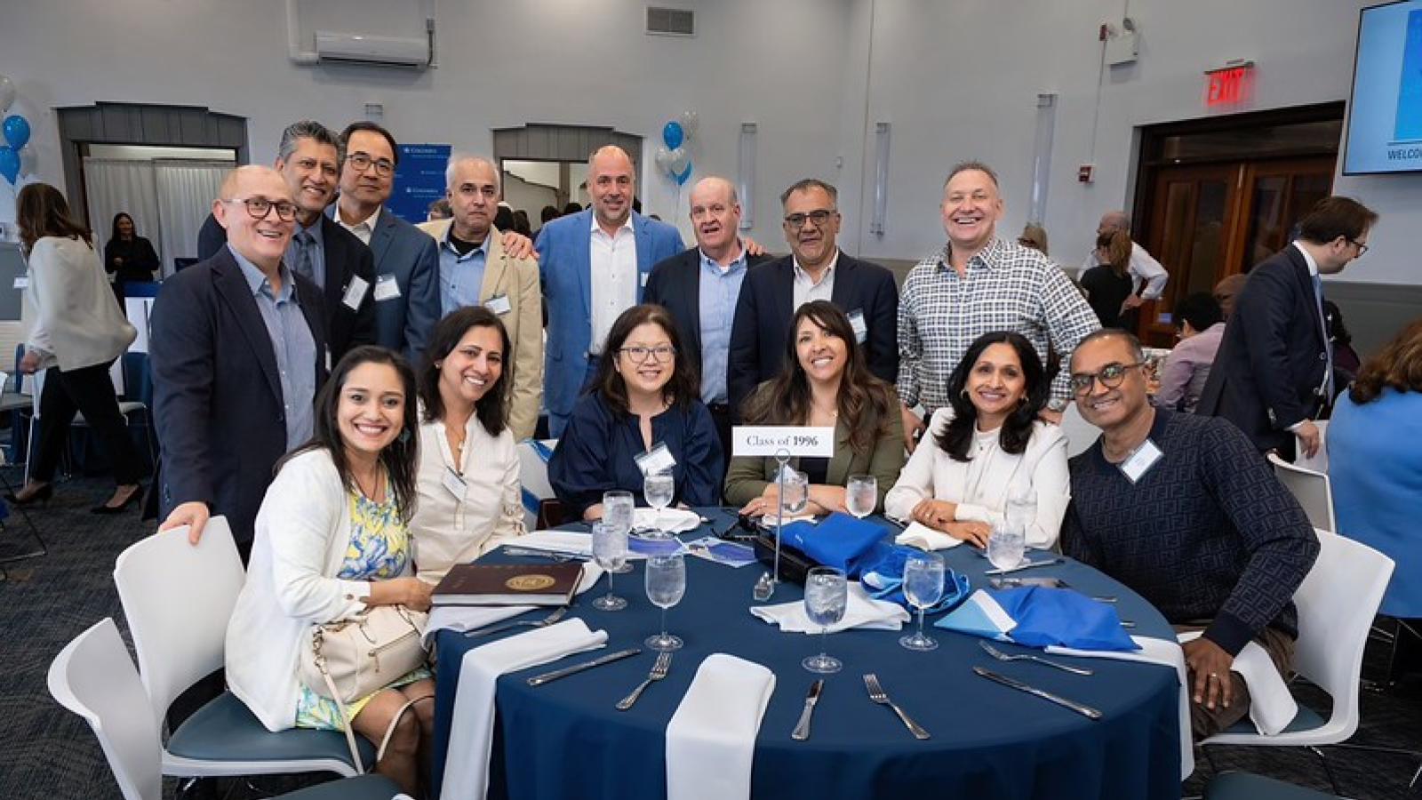 Alumni gathered around a table posing for the camera