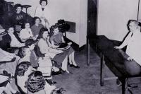 Image of a classroom where a teacher is teaching students and mostly they are female.