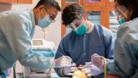 dentist instructing two residents during dental procedure