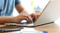 A man types on a laptop keyboard.