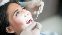 Woman smiling while receiving dental exam