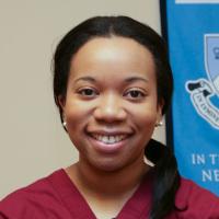 An adult female of African descent with a college of dental medicine banner in the background